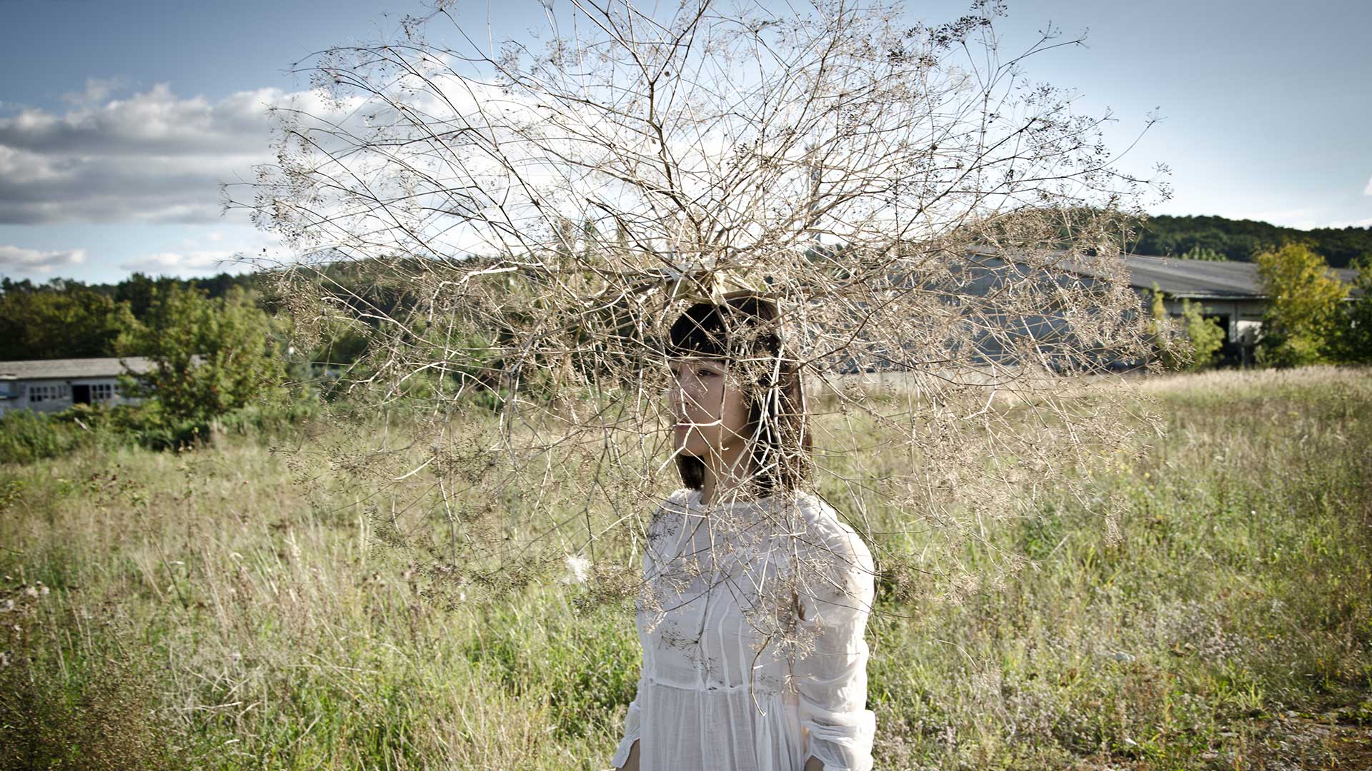 Eine Frau auf einer Wiese mit einem Ast als Hut.